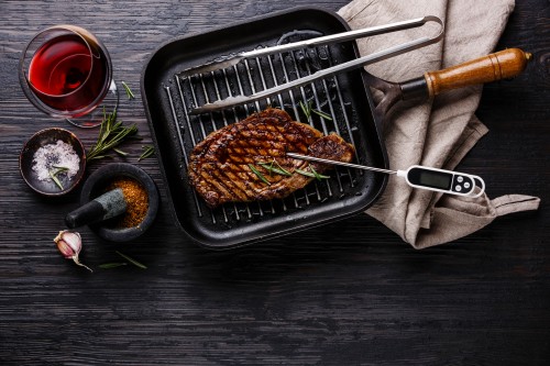 BBQ accessories including meat thermometer and grilling pan.
