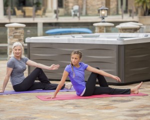 Grandmother and granddaughter doing yoga outside the hot tub.